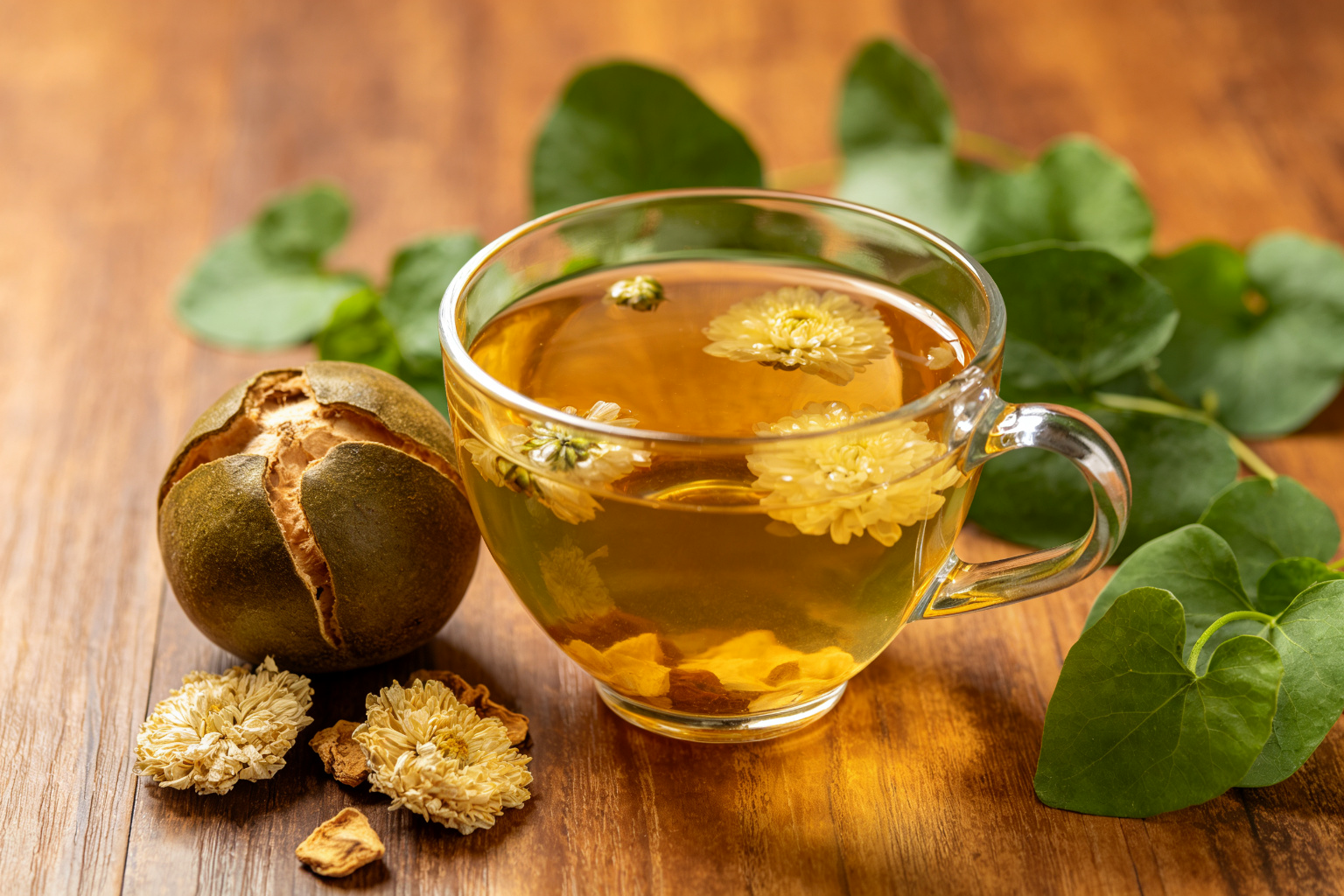 Monk fruit, chrysanthemum and houttuynia herbal tea drink in glass cup on wooden surface