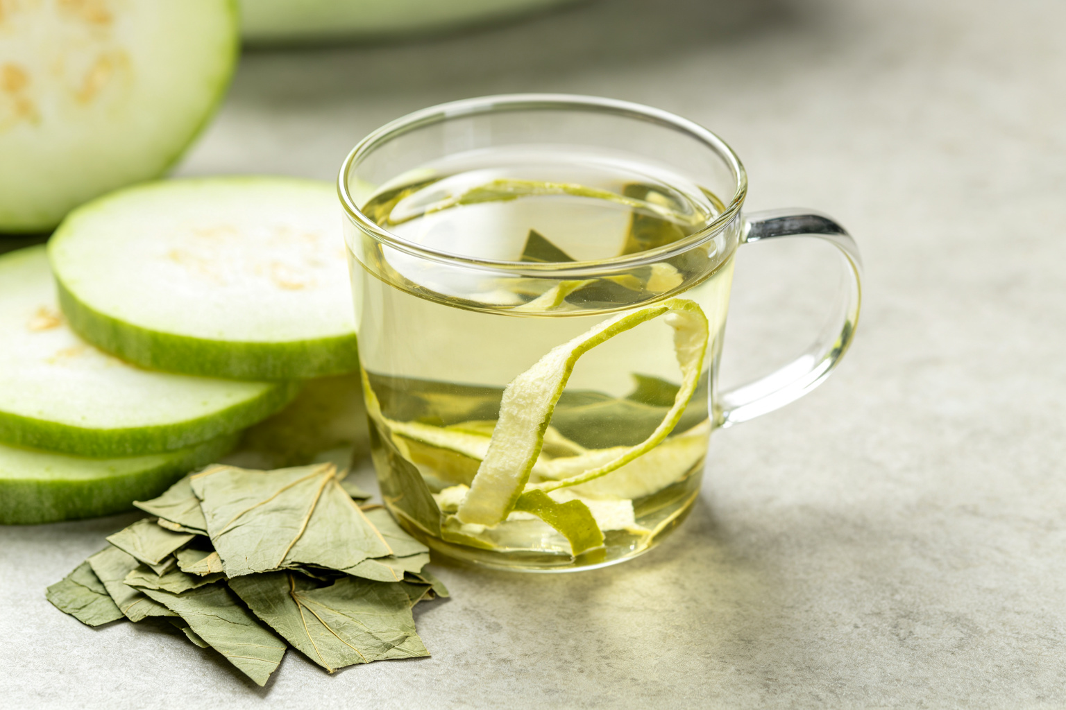 Winter melon peel and lotus leaf herbal tea in a clear glass mug with fresh ingredients